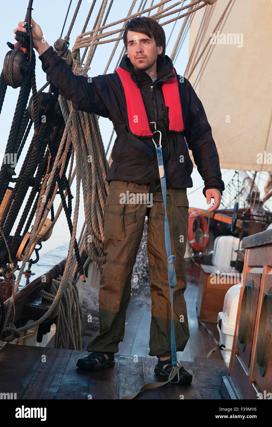 Young sailor onboard with sails behind him Stock Photo