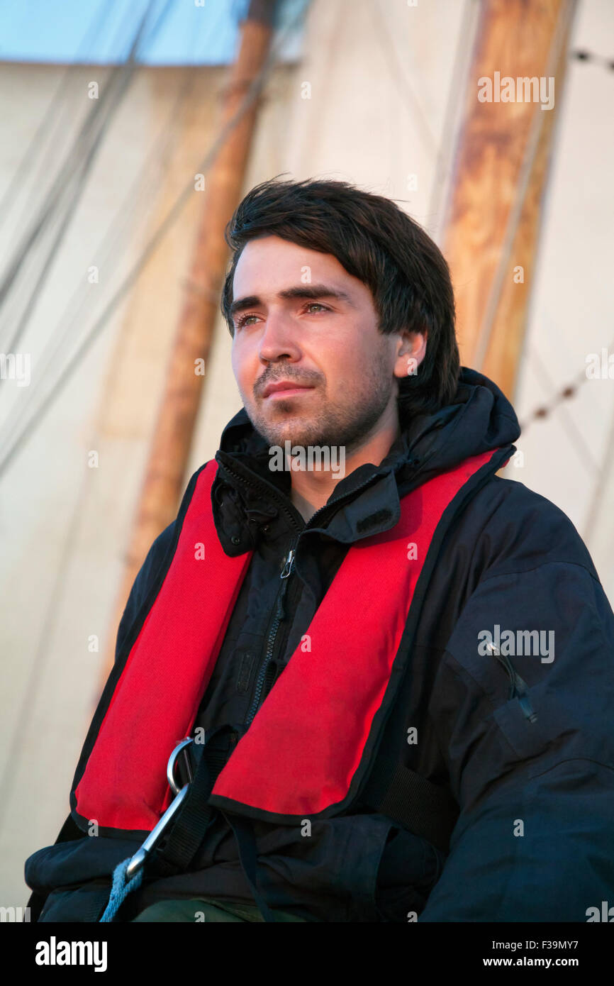 Young sailor on board with sails behind him Stock Photo