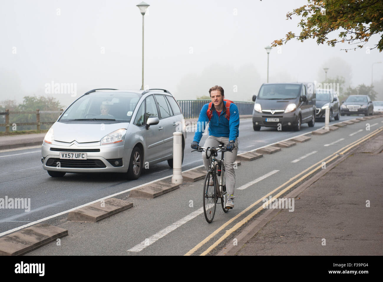 Cyclists cycling in fog on Donnington Bridge in Oxford, which has a segregated cycle lane to protect riders from traffic. Stock Photo