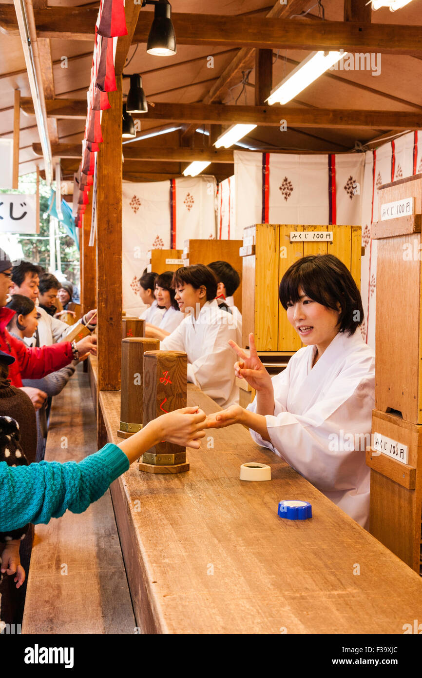 Japan, Nishinomiya shrine, New year Day, Shogatsu. Woman buying omikuji ...