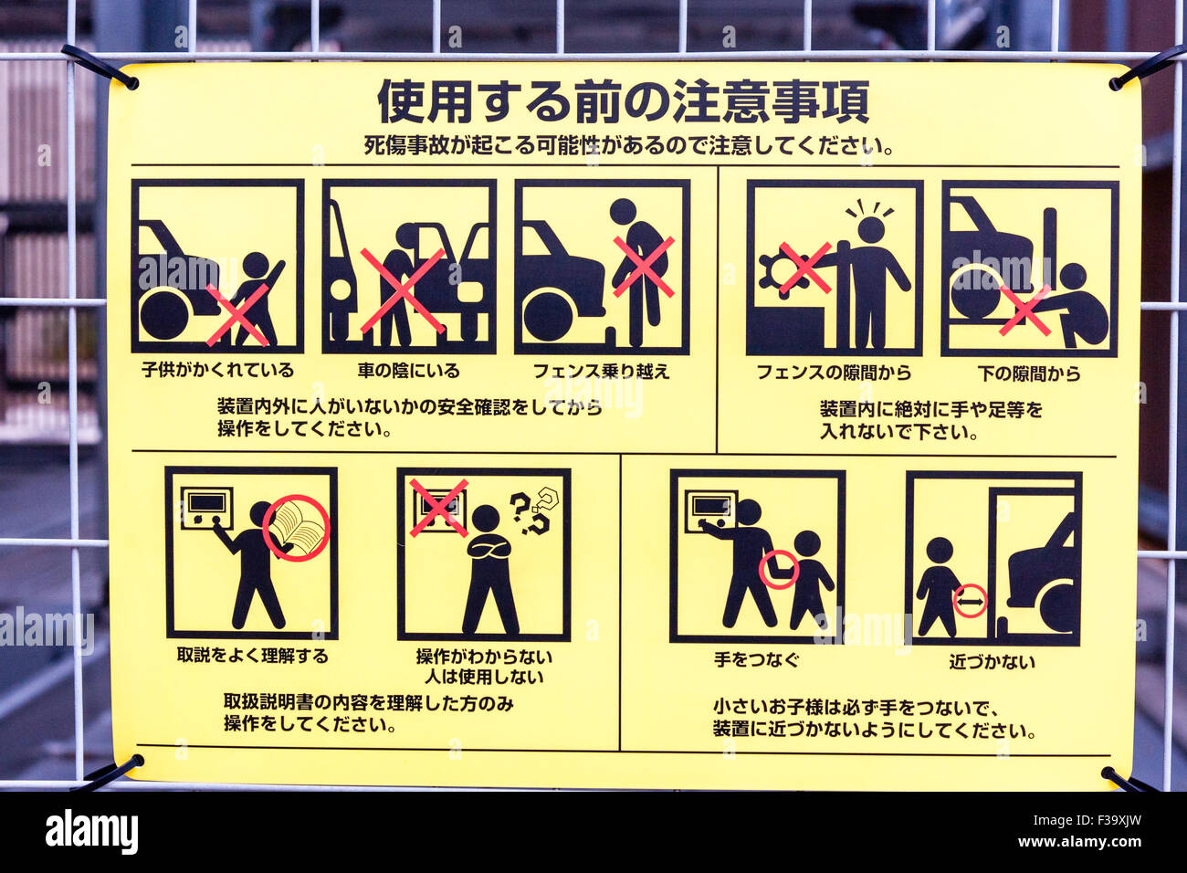 Japan, yellow information sign on how to use multi-storey car parking space with diagrams of what to do and warnings of the dangers. Stock Photo