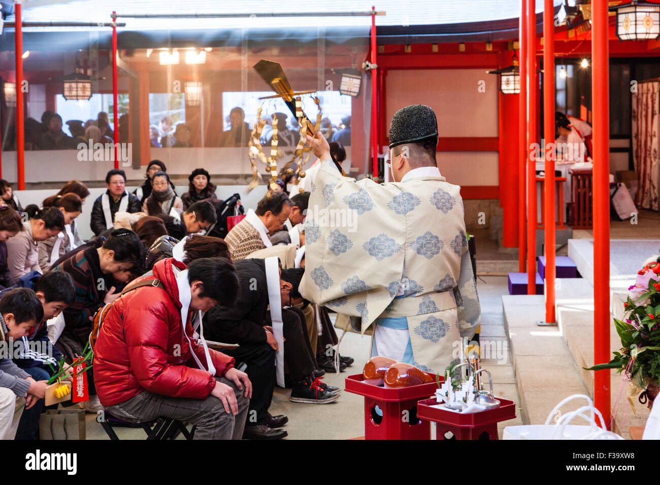 Japanese Shinto priest, kannushi, wearing eboshi hat and kariginu garment performing a blessing on seated people at Ikuta Shrine in Kobe at New year. Stock Photo