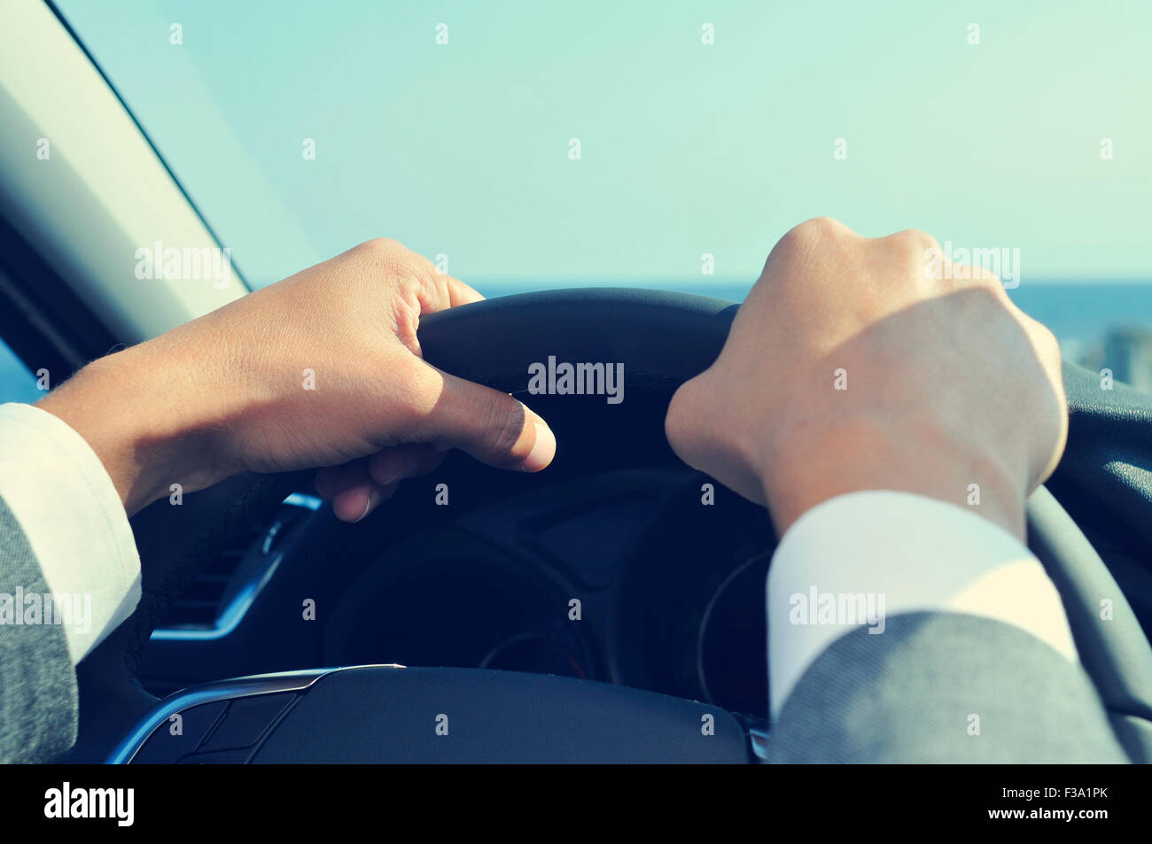 closeup of a young man wearing a gray suit driving a car, with a filter effect Stock Photo