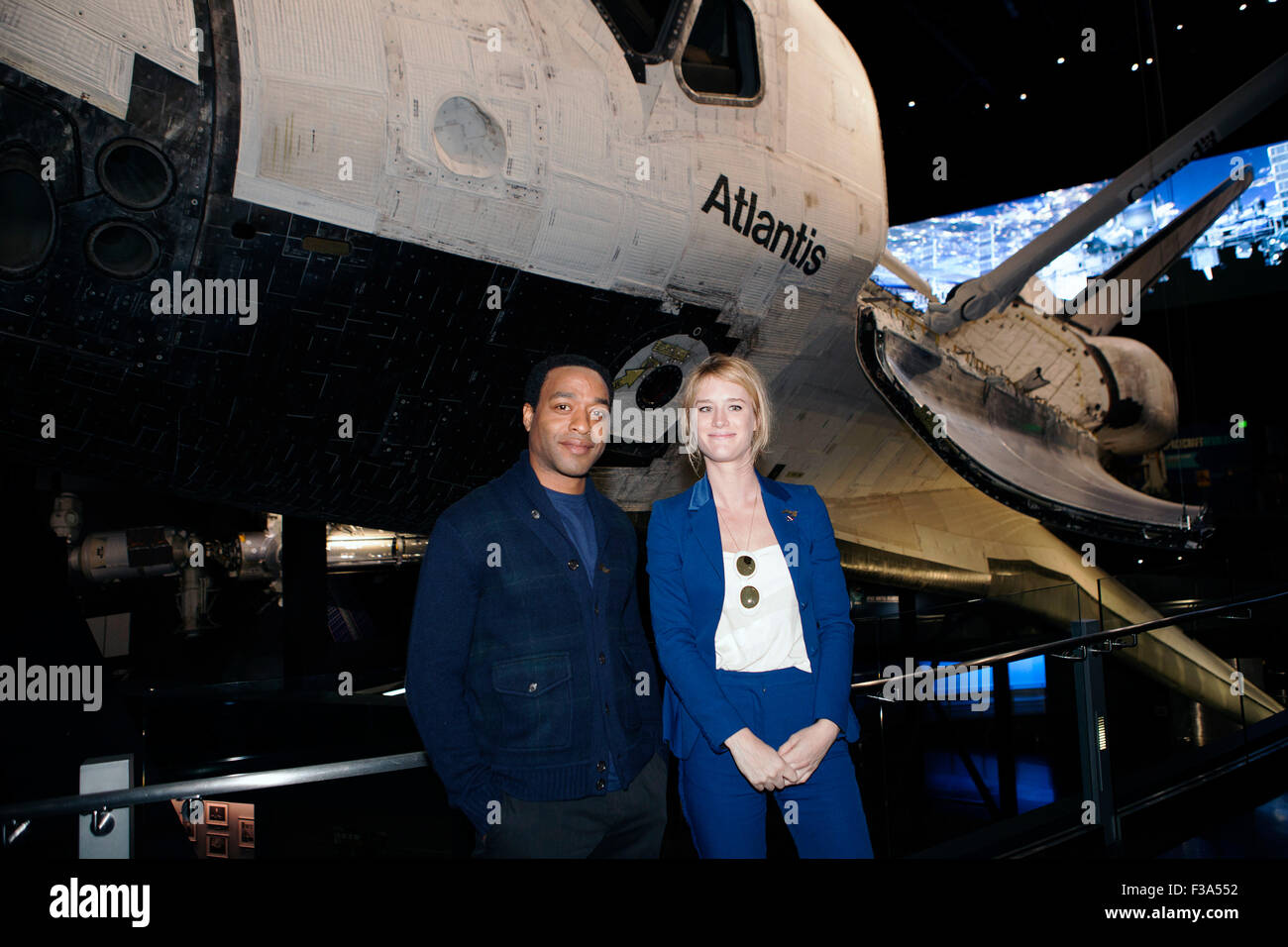 Actors Chiwetel Ejiofor and Mackenzie Davis pose for a photograph in front of Atlantis during a tour of Space Shuttle display at NASA's Kennedy Space Center Visitor Complex October 1, 2015 in Cape Canaveral, Florida. Ejiofor and Davis star in the movie The Martian. Stock Photo