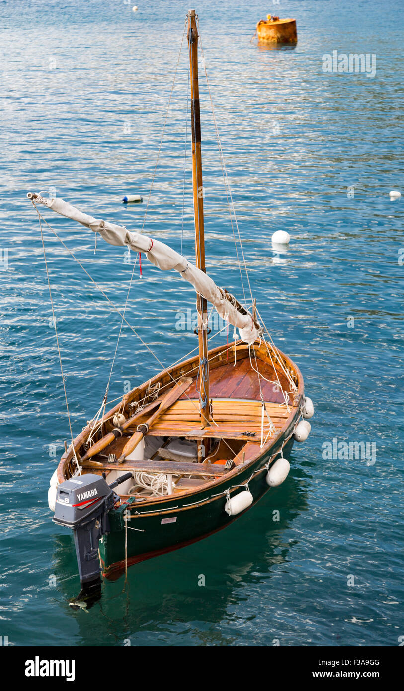 Empty wooden sailboat with small motor and fenders around 