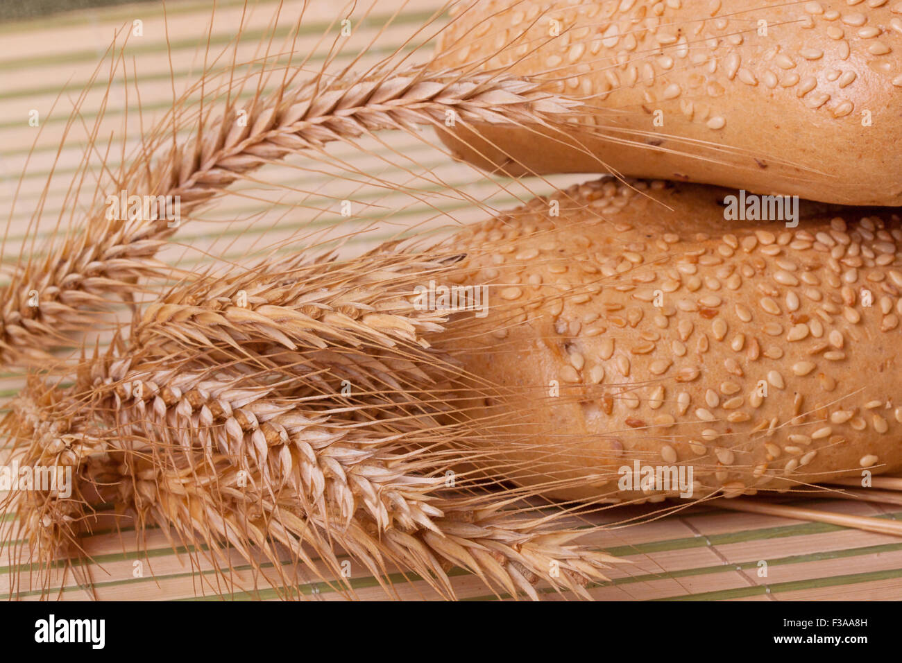 two buns with wheat spikelets on a bamboo mat Stock Photo