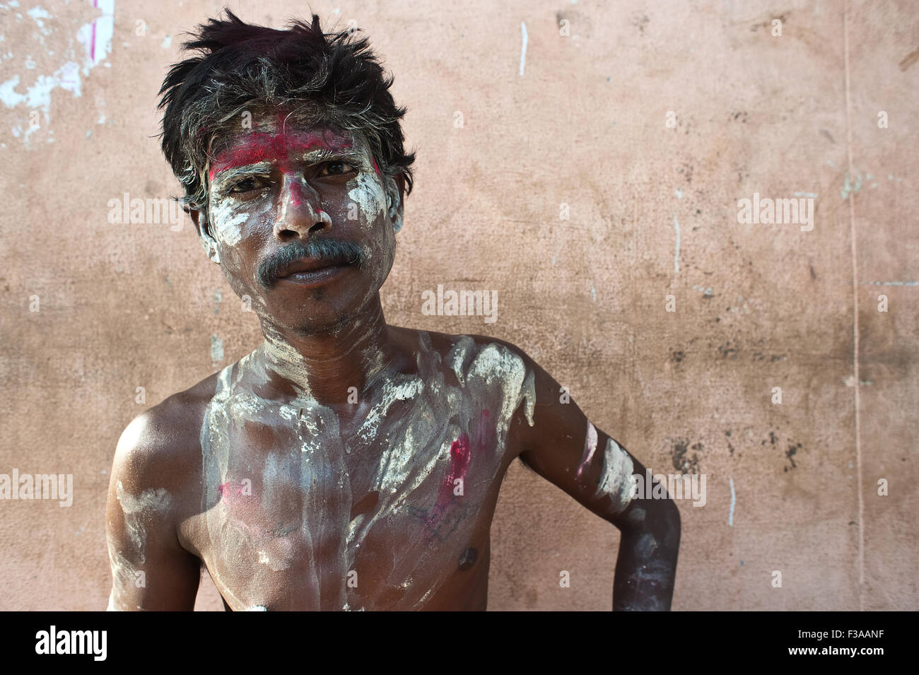 Man begging with the face and body painted red and white ( India) Stock Photo