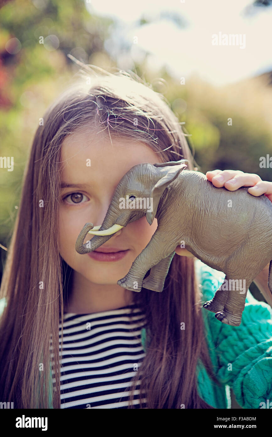 Girl covering one eye with a toy elephant Stock Photo