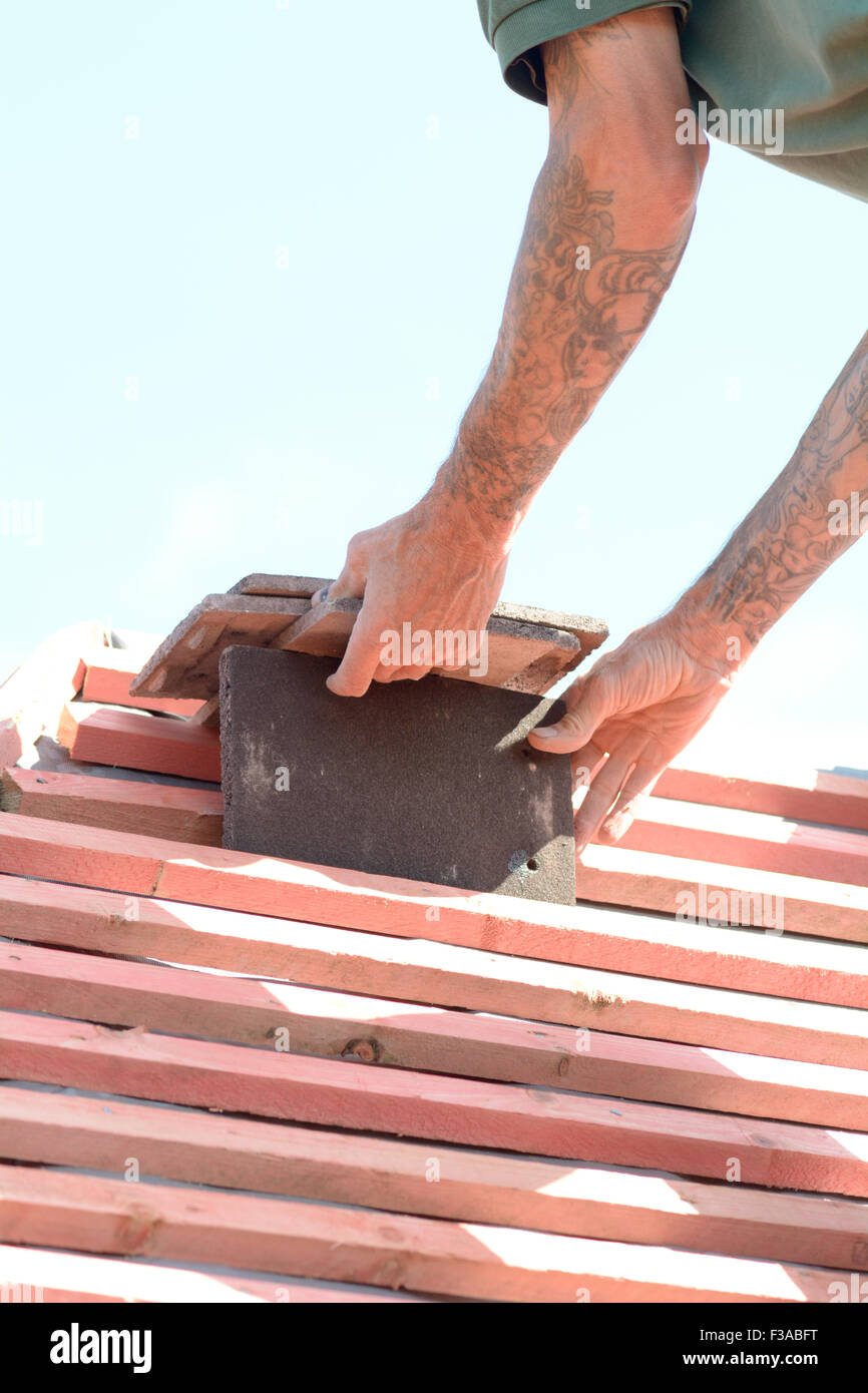 Roofer stacking tiles on roof ready for quick and efficient fixing in