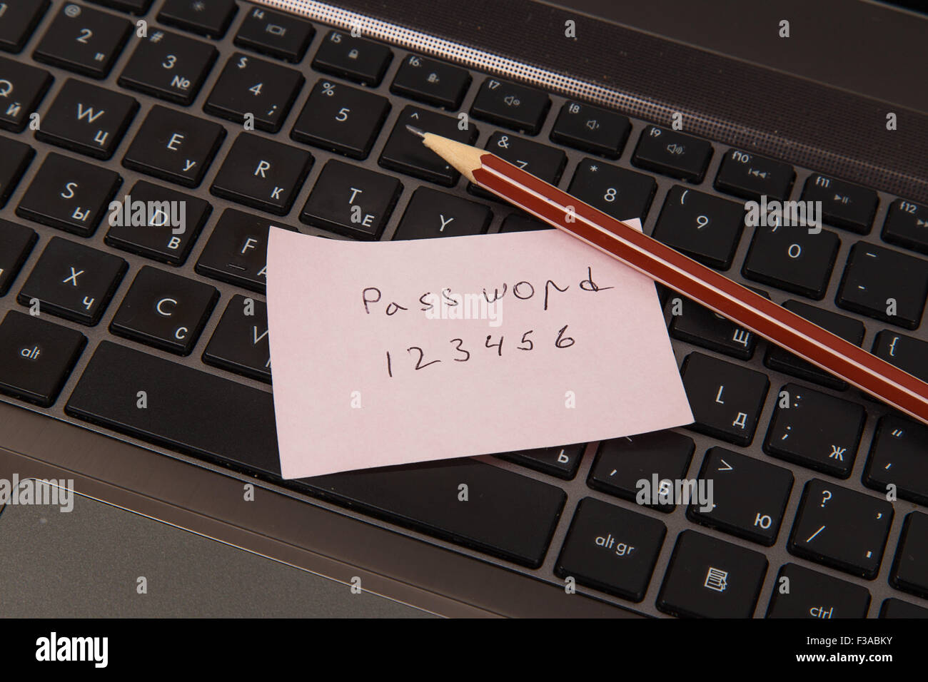 Sticky note with password and pencil on black laptop Stock Photo