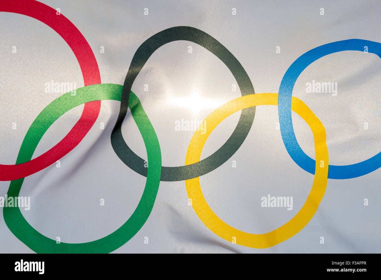 RIO DE JANEIRO, BRAZIL - FEBRUARY 12, 2015: An Olympic flag flutters in the wind backlit against bright sun. Stock Photo