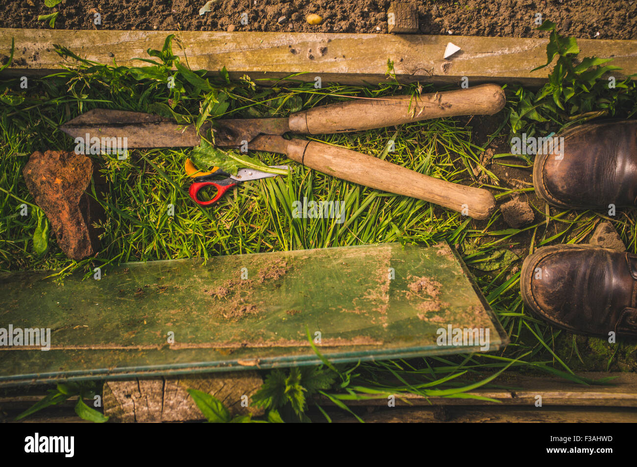 garden scene with tools and boots scissors rock and grass Stock Photo