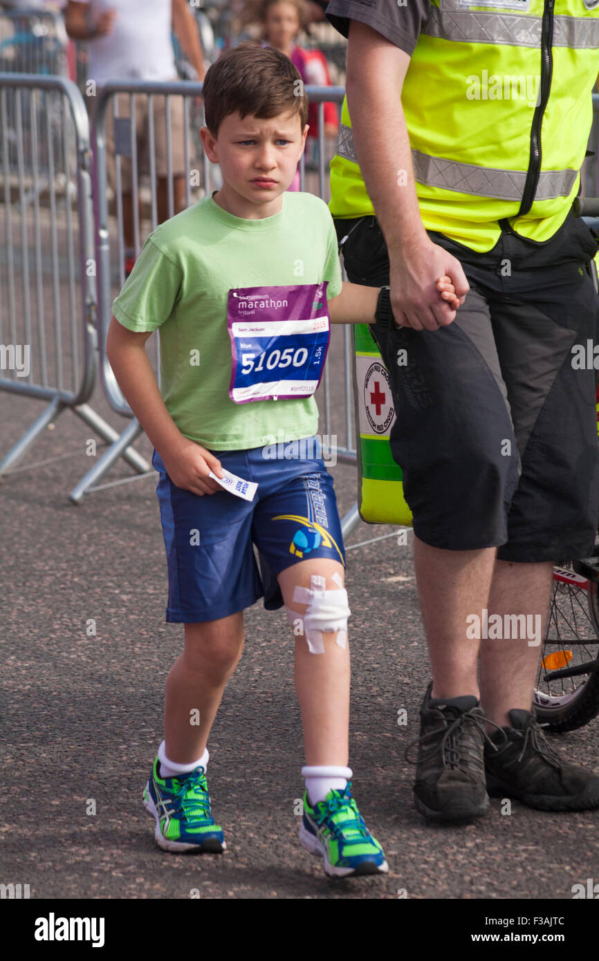 Bournemouth, Dorset, UK. 3 October 2015. Children aged 6-8 years take part in the  Junior 1.5k Run race at the Bournemouth Marathon Festival. First Aider helps young boy who fell and hurt his knee.  Credit:  Carolyn Jenkins/Alamy Live News Stock Photo