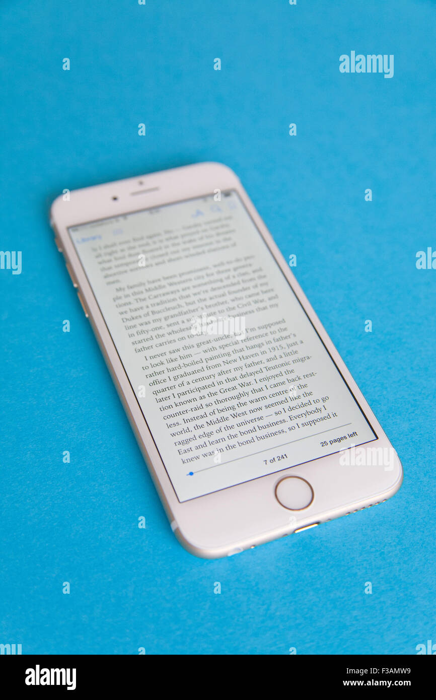 Reading an ebook on a Gold and white Apple iPhone 6 againdt a blue background Stock Photo