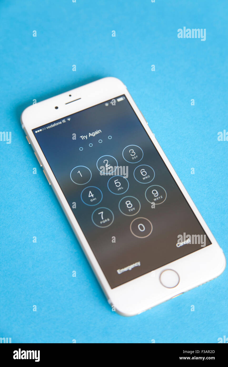 Gold and white Apple iPhone 6 with log in screen for password, against a blue background Stock Photo