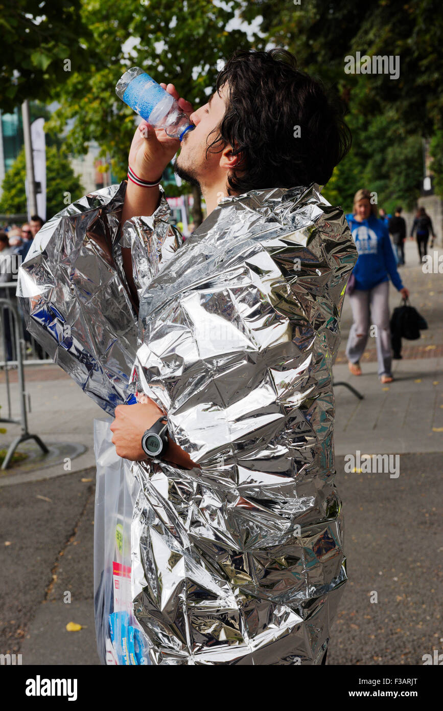 Half marathon competitor cools down in thermal silver wrap while recovering after finish, Bristol 2015 run Stock Photo