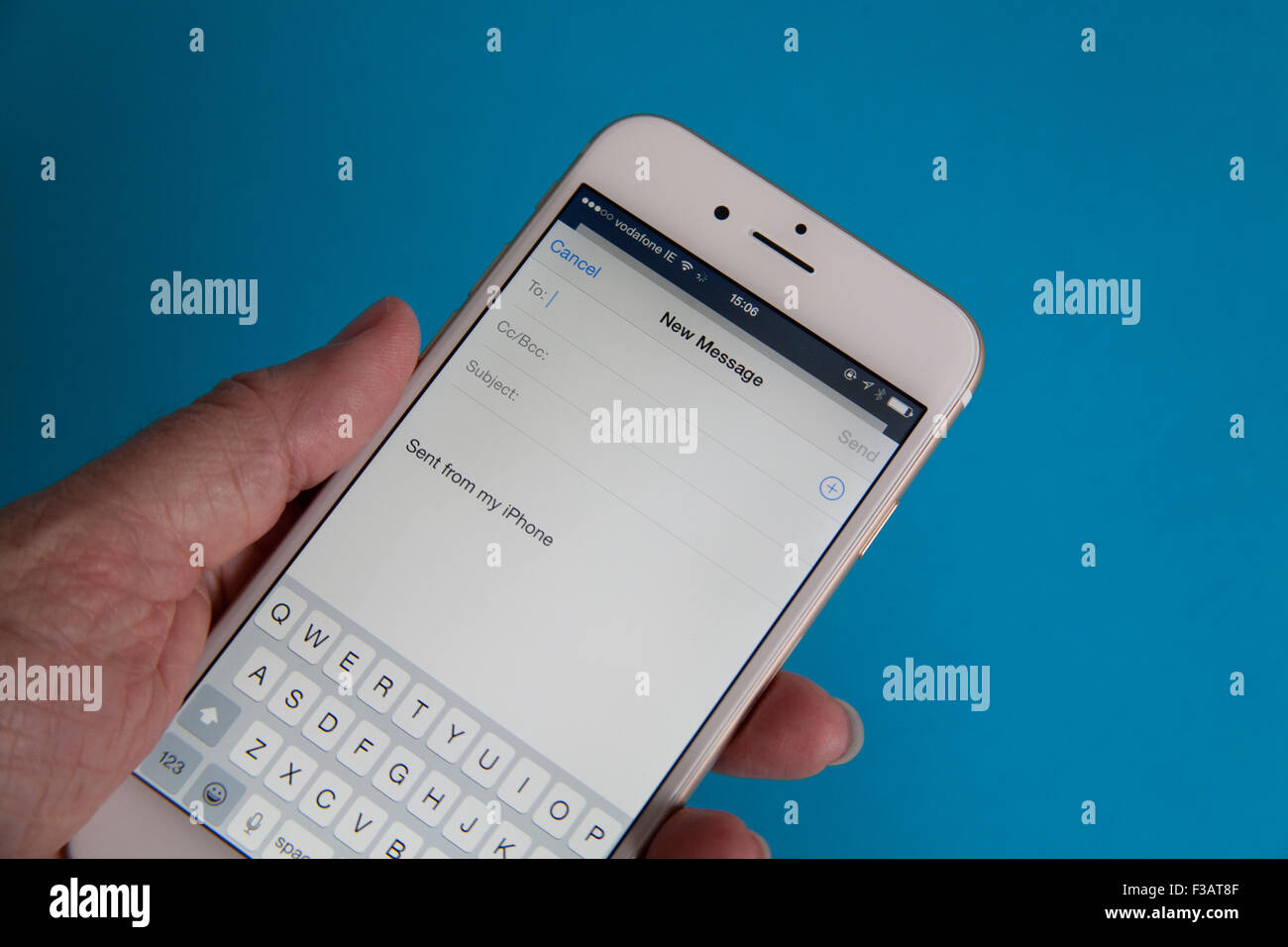 Sending an email on a Gold and white Apple iPhone 6 against a blue background Stock Photo