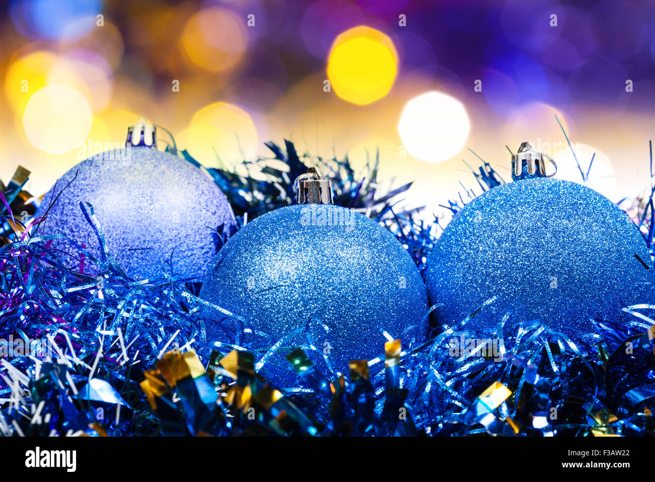 Xmas still life blue balls, tinsel with blurred yellow and blue Christmas lights bokeh