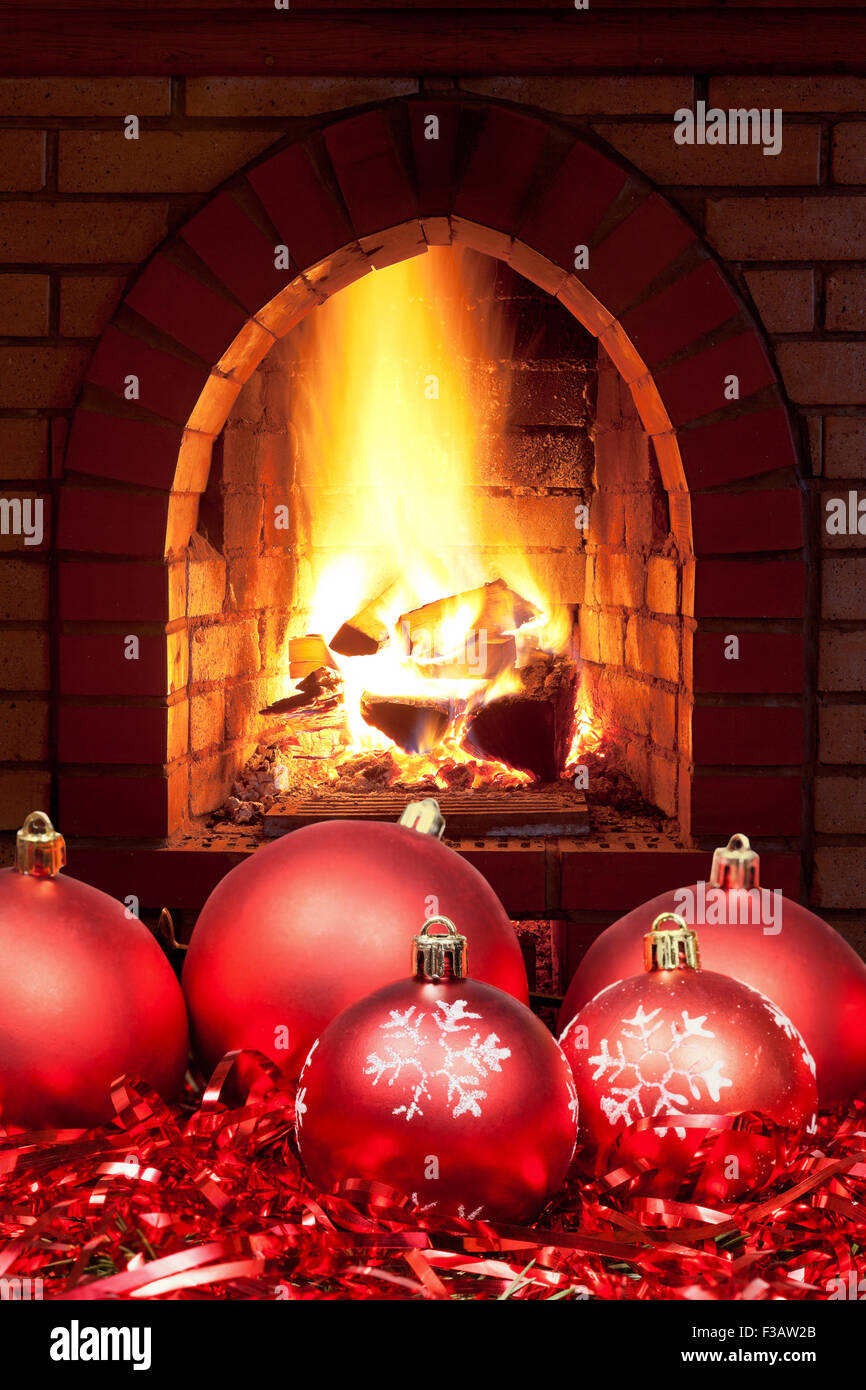 red Xmas baubles and tinsel with open fire in home fireplace Stock Photo