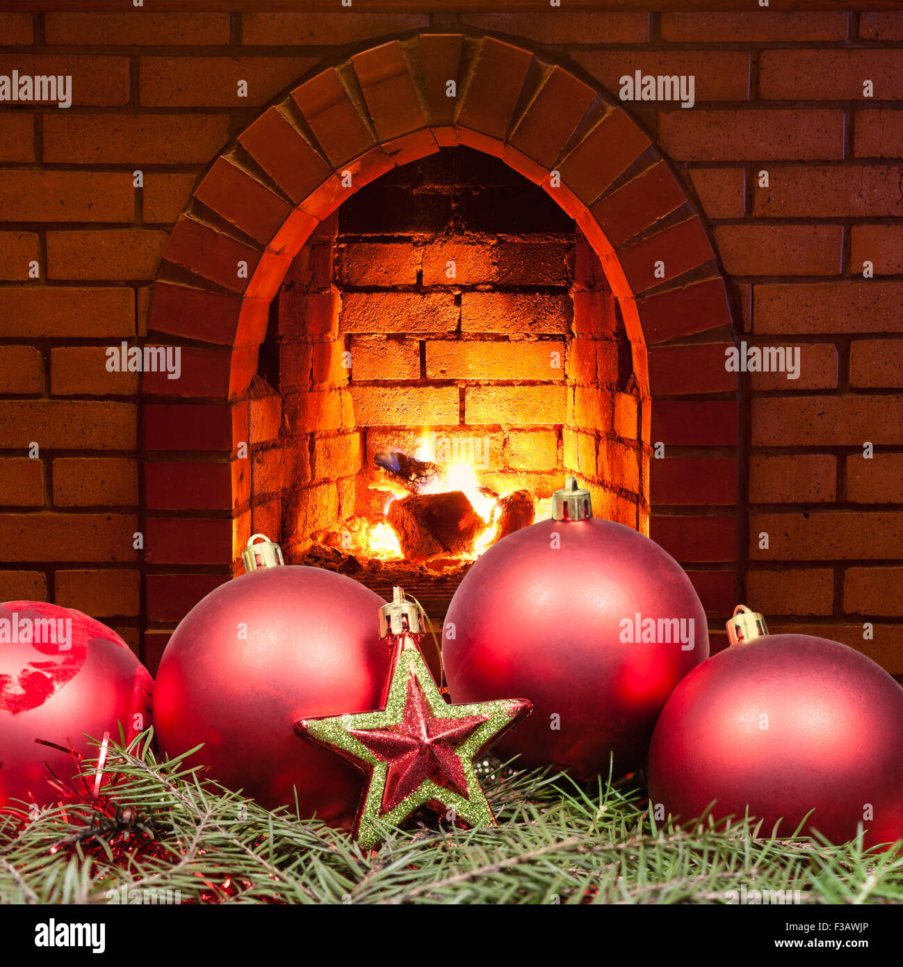 red star and Xmas bubles on green spruce tree with open fire in home fireplace Stock Photo