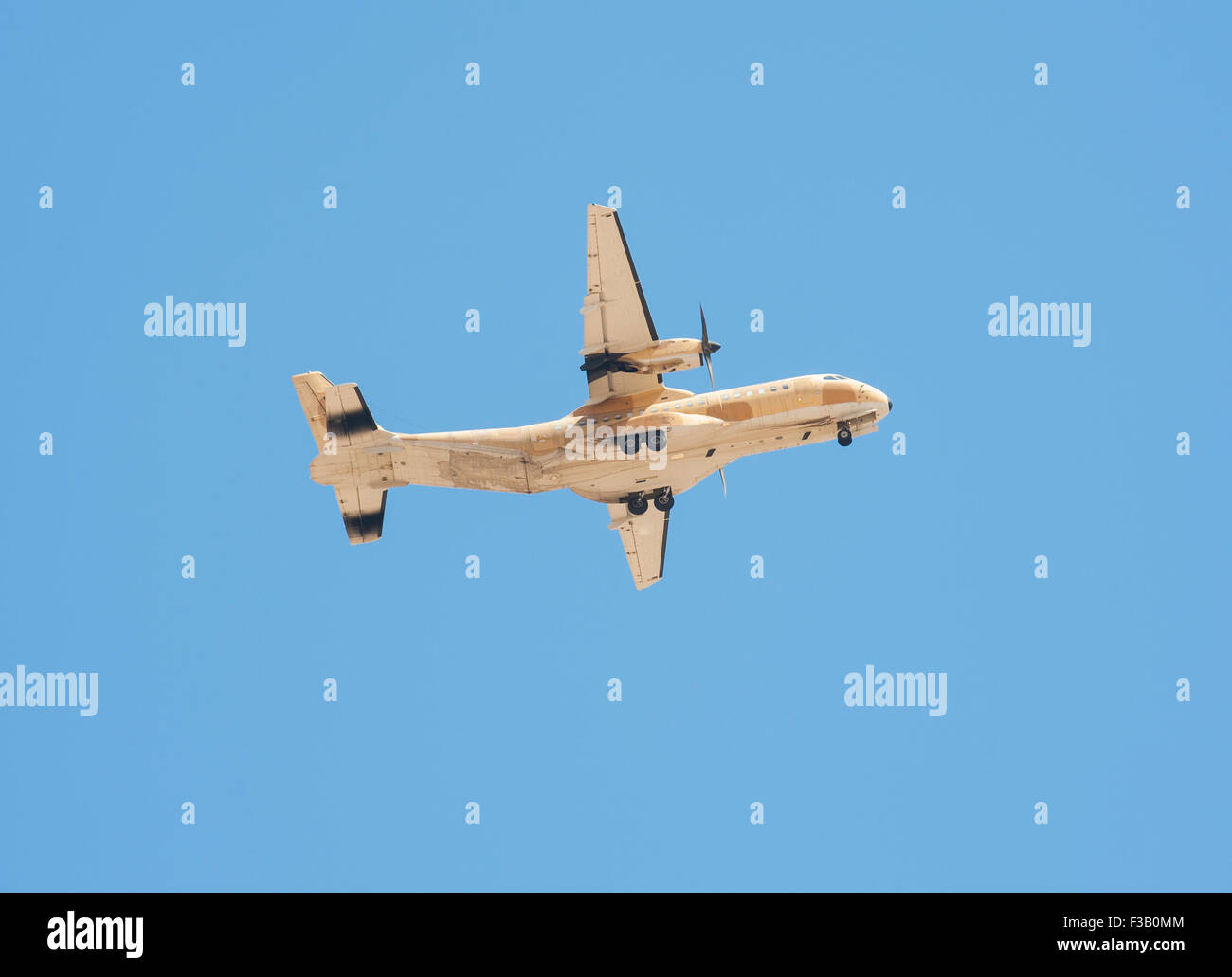 Large military tactical transport aircraft turboprop aeroplane in flight against blue sky background Stock Photo