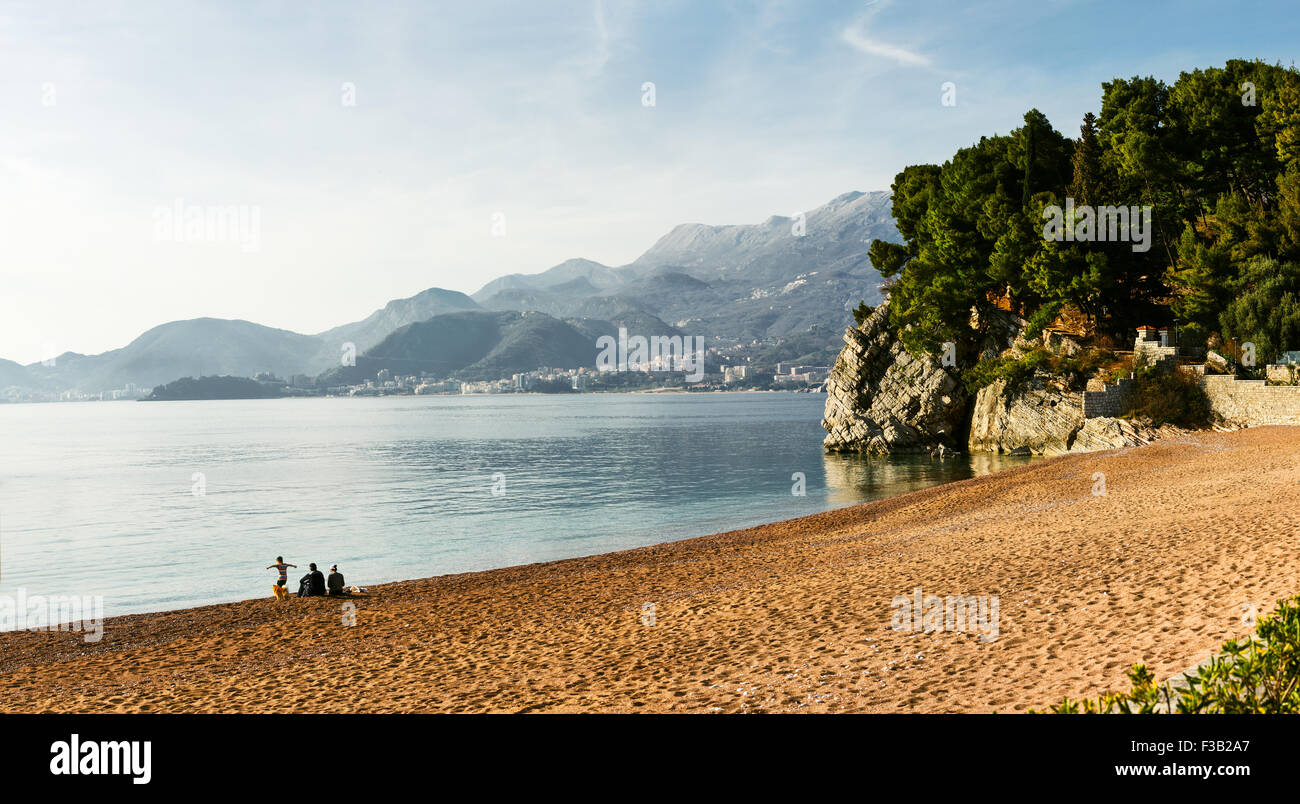 Young family on a deserted beach and mountains background landscape. Sveti Stefan, Montenegro. Stock Photo