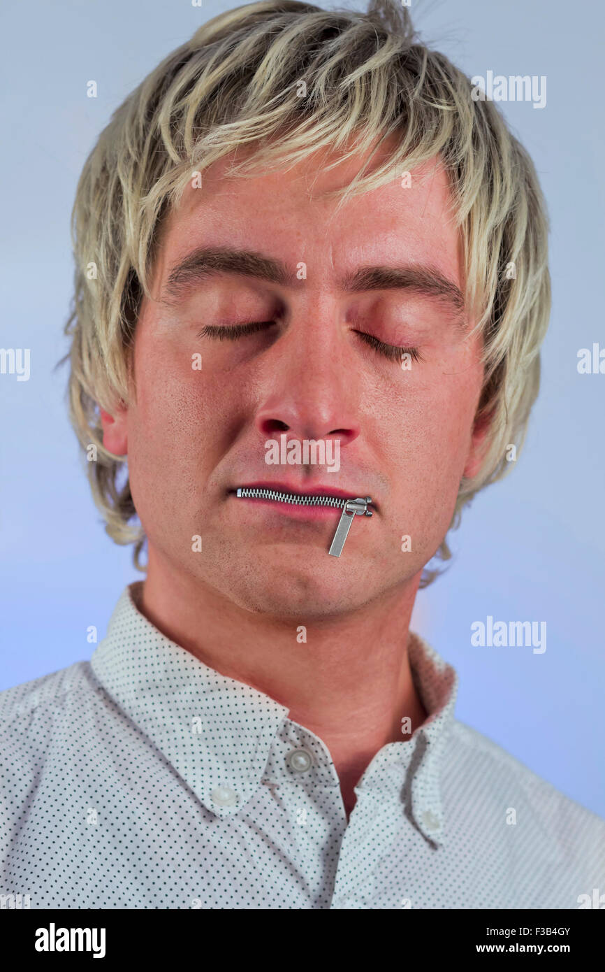 Zipper on mouth silences silly blonde haired man Stock Photo