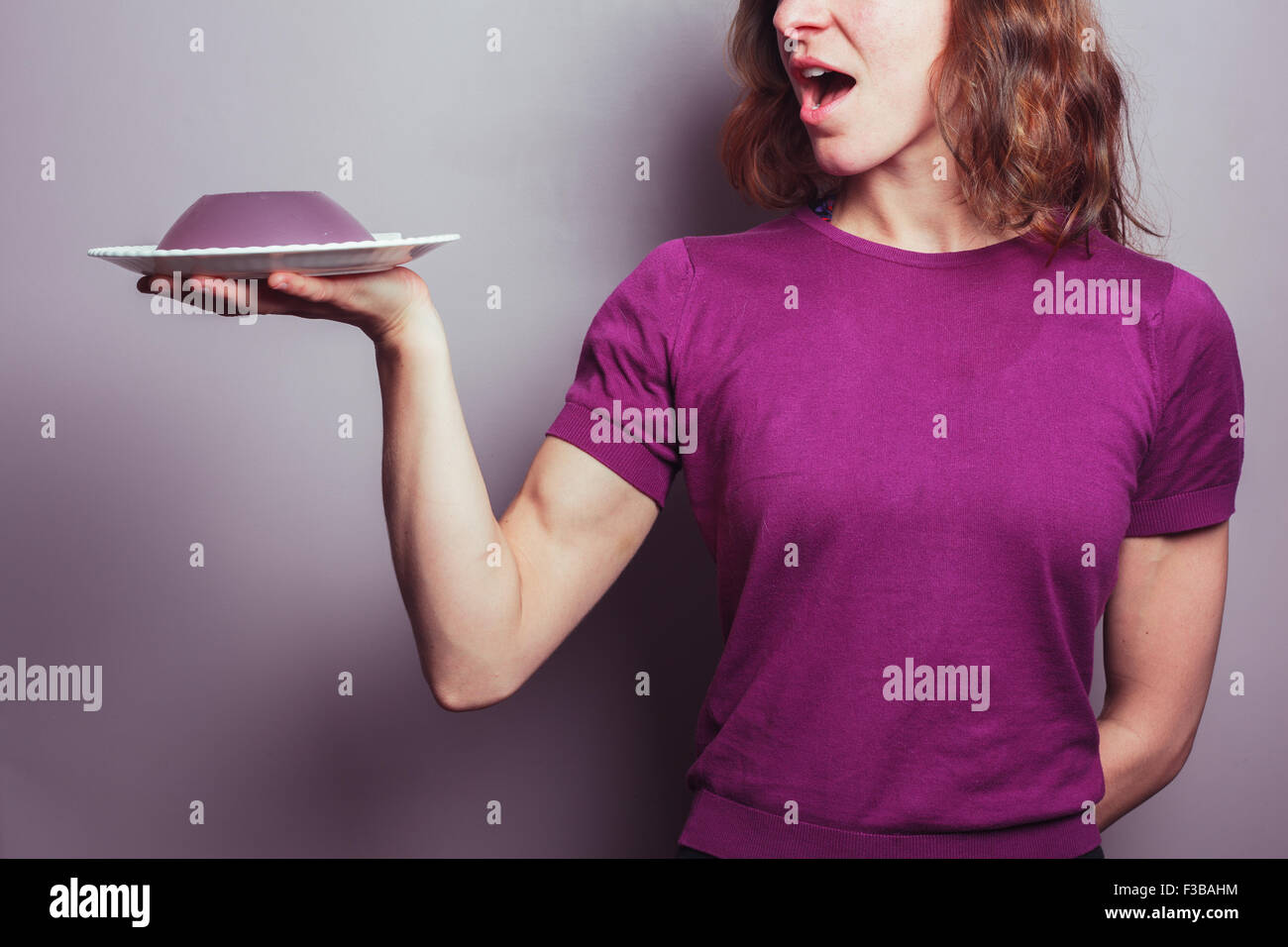 A young woman in a purple top is presenting a plate of jelly Stock Photo