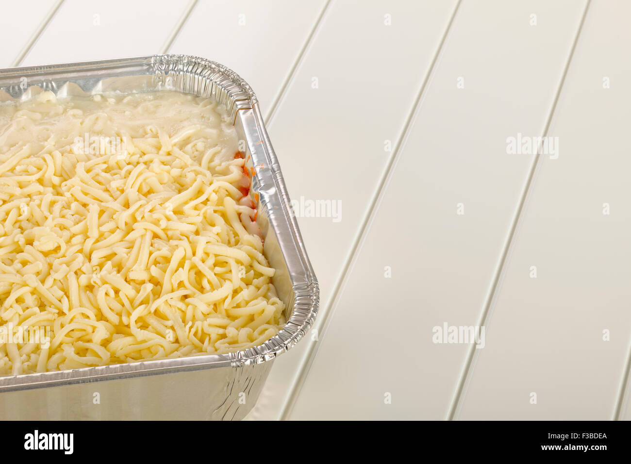 Frozen lasagna in the mold of aluminum on white wooden background Stock