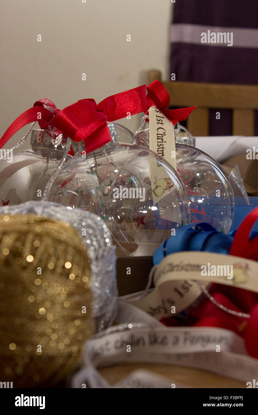 Getting ready for Christmas with baubles and red ribbon bows, glittery stars and gold string. festive fun on a craft table. Stock Photo