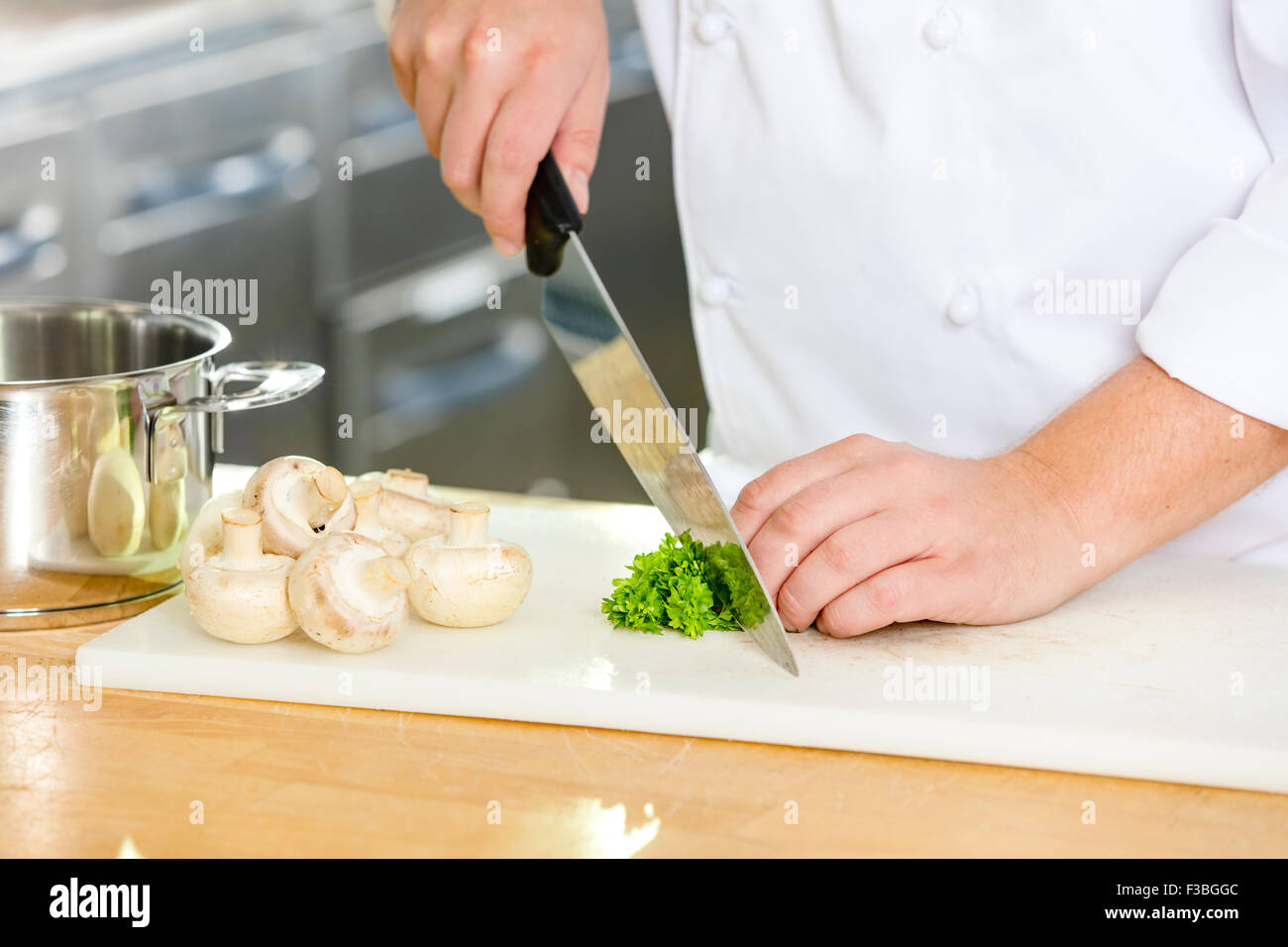 Professional chef cutting parley and mushrooms Stock Photo