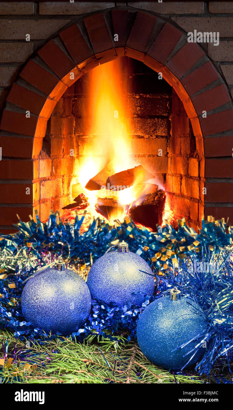 blue Christmas balls on green spruce tree with open fire in home fireplace Stock Photo