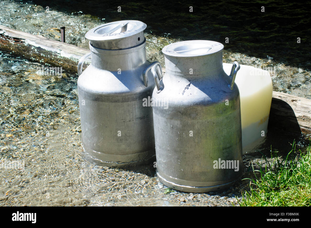 Metal Milk urns in dairy farm cooling in spring water. Photographed in Tirol, Austrial Stock Photo