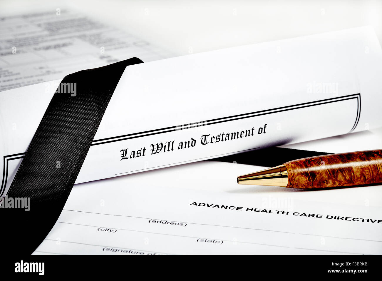 Last Will and Testament rolled up with advance health care directive and tax return in background isolated on white with a pen a Stock Photo