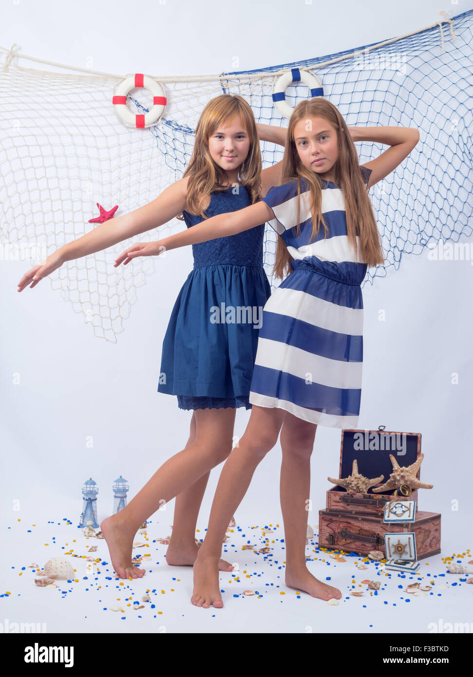 Two beautiful teen girls looking forward and fishing net with lifebuoys on background Stock Photo