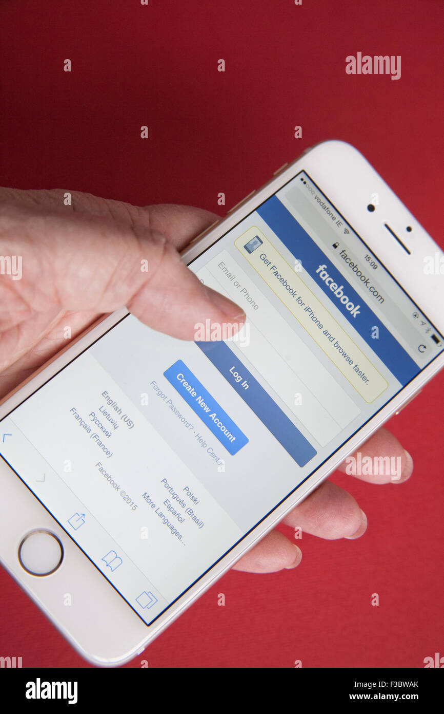 Gold and white Apple iPhone 6 with Facebook log in screen against a red ...