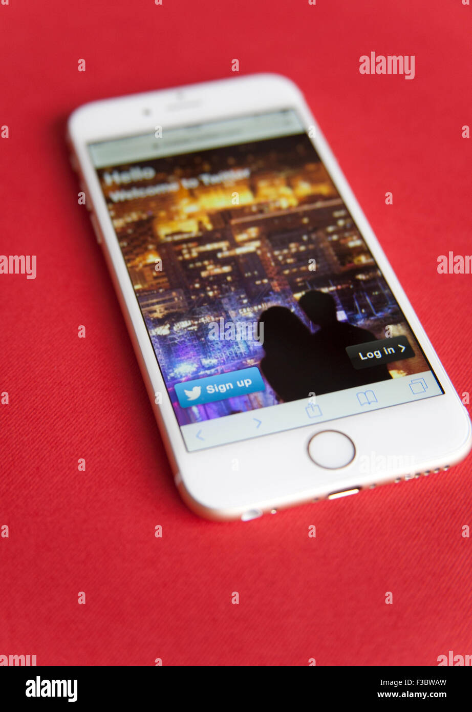 Log in screen for a Twitter account on an Gold and white Apple iPhone 6 against a red background Stock Photo