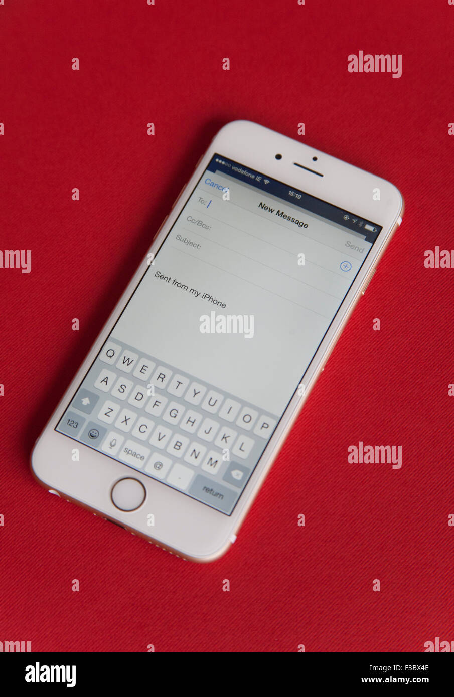 Sending an email on a Gold and white Apple iPhone 6 against a red background Stock Photo