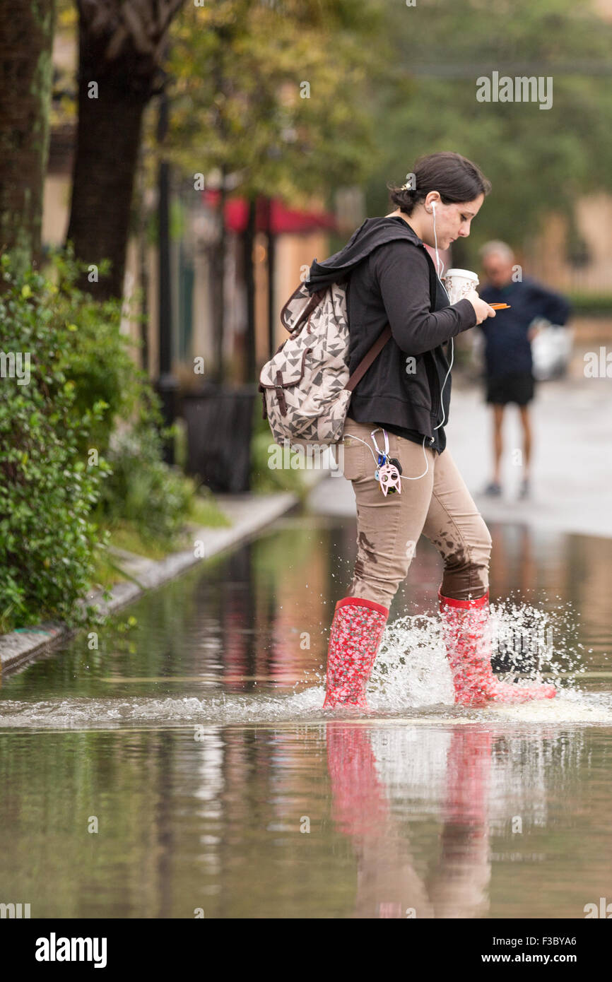 Charleston, South Carolina, USA. 4th October, 2015. A women texts as she walks through floodwater across Church Street in the historic district as Hurricane Joaquin brings heavy rain, flooding and strong winds as it passes offshore October 4, 2015 in Charleston, South Carolina. Stock Photo