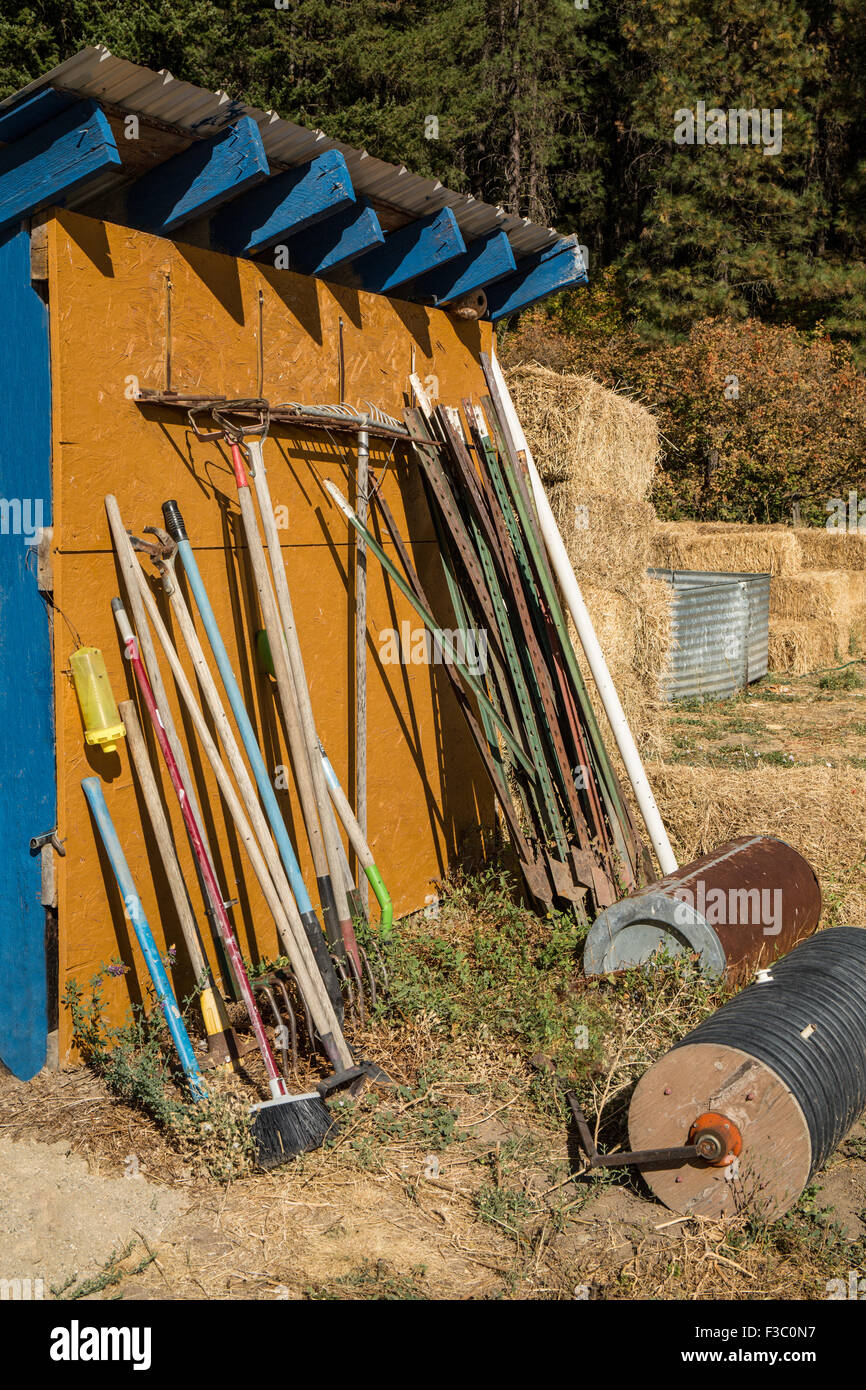 Tool shed with a variety of garden tools including rakes, brooms, stakes, and rollers, in Leavenworth, Washington, USA Stock Photo