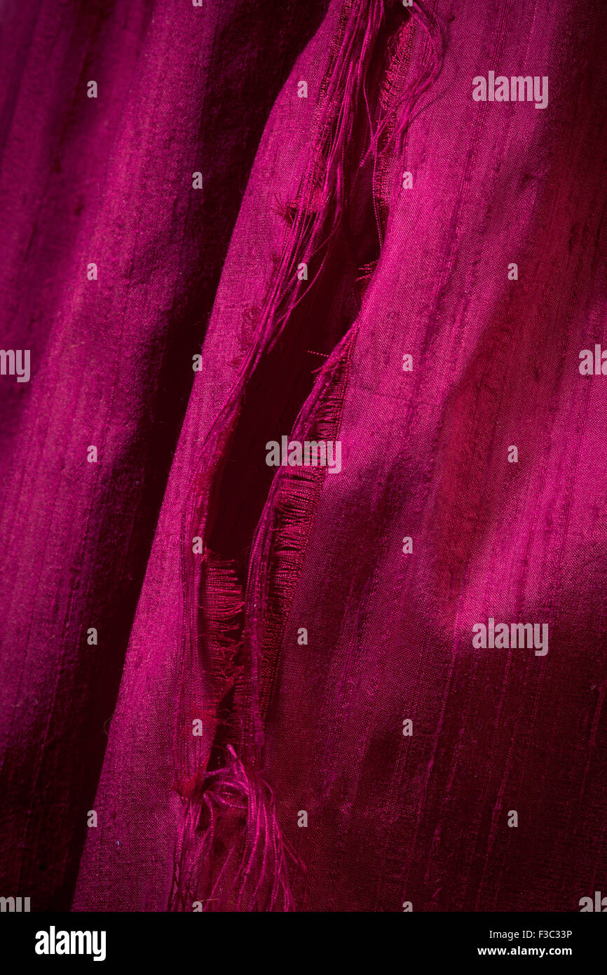 A piece of hot pink colored ripped silk fabric. Stock Photo