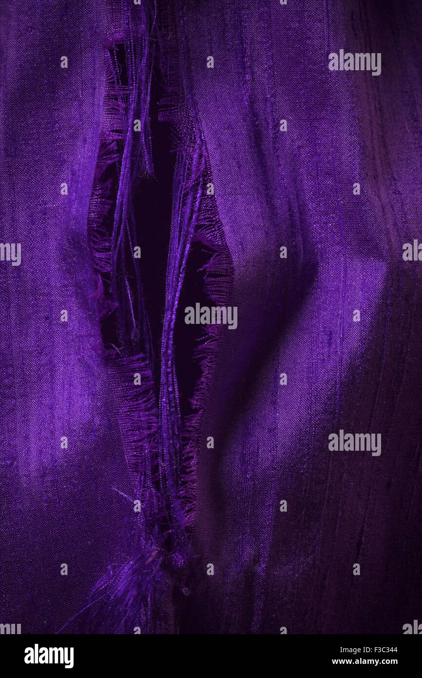 A piece of deep rich purple ripped silk fabric. Stock Photo