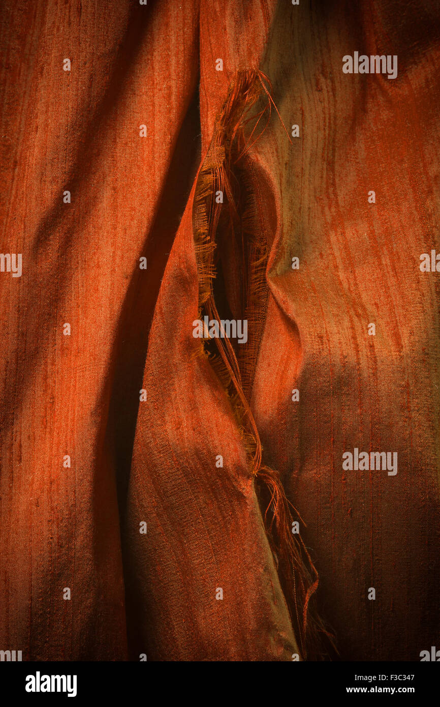A piece of deep orange ripped silk fabric. Stock Photo