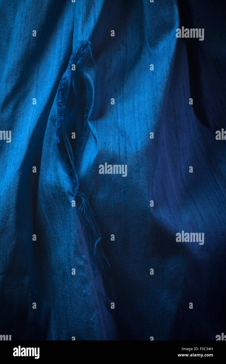 A piece of blue ripped silk fabric. Stock Photo