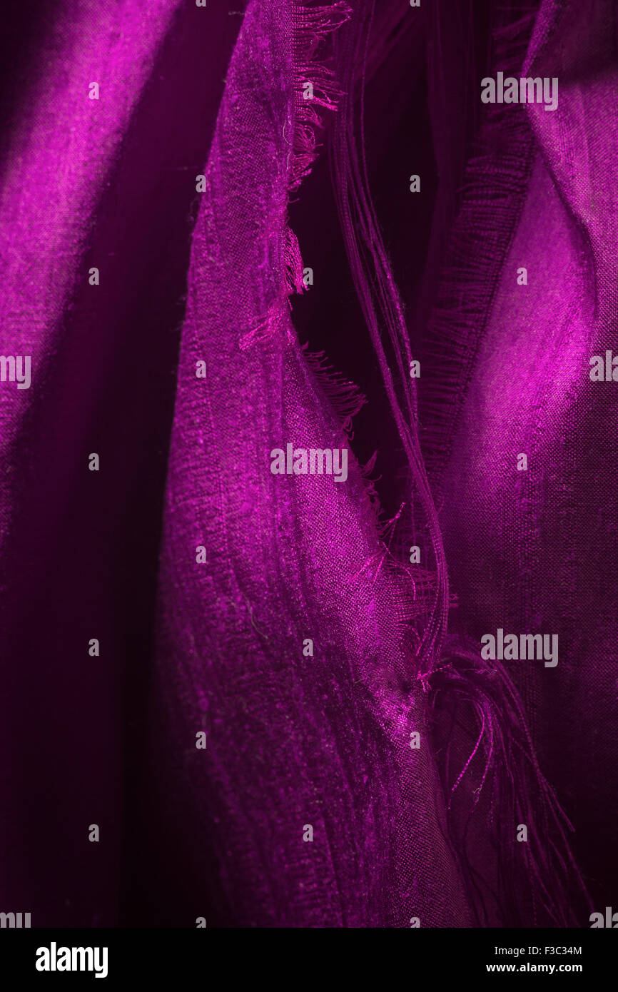 A piece of magenta ripped silk fabric. Stock Photo