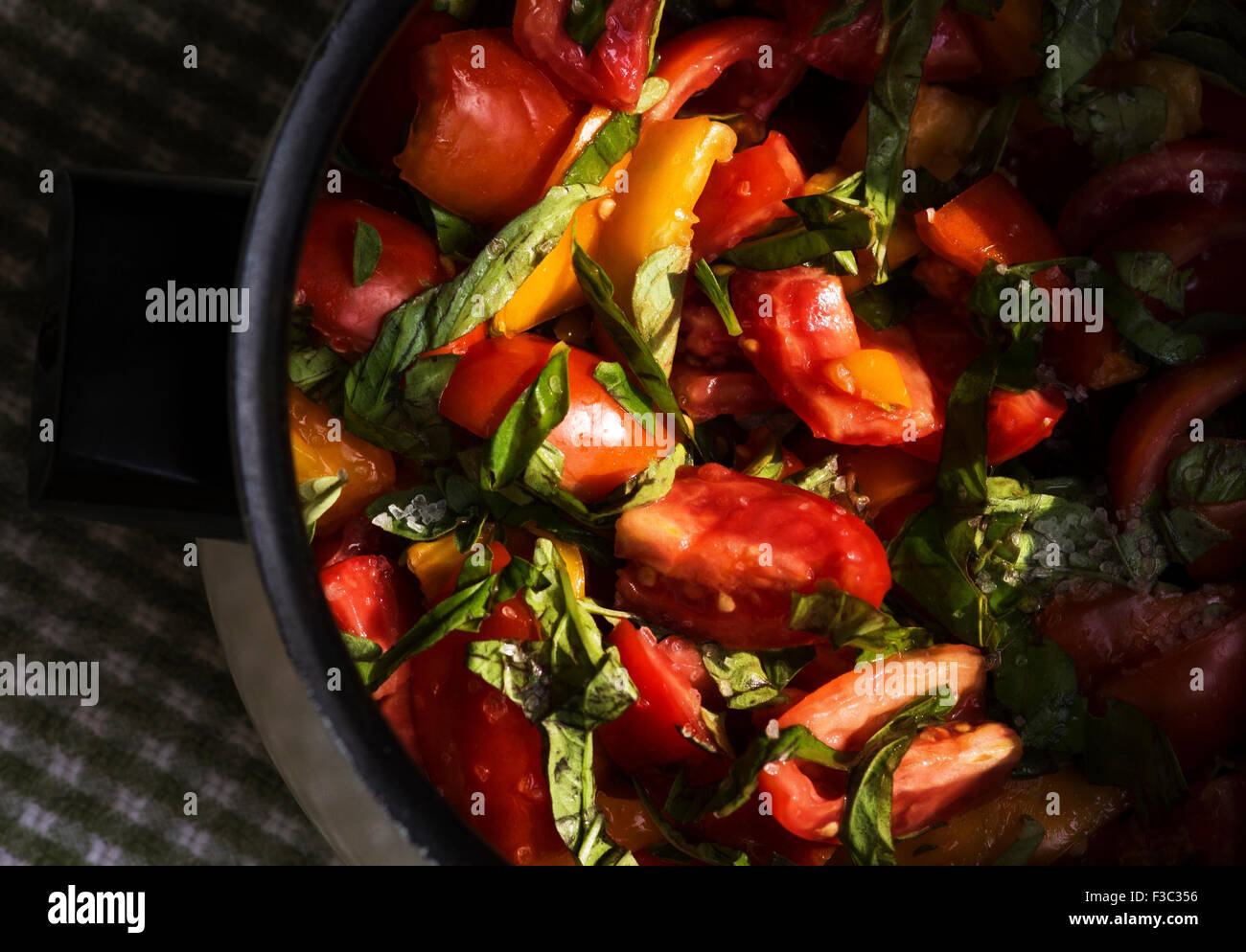 Fresh tomato and basil chopped up and put into a pot ready to cook. Stock Photo