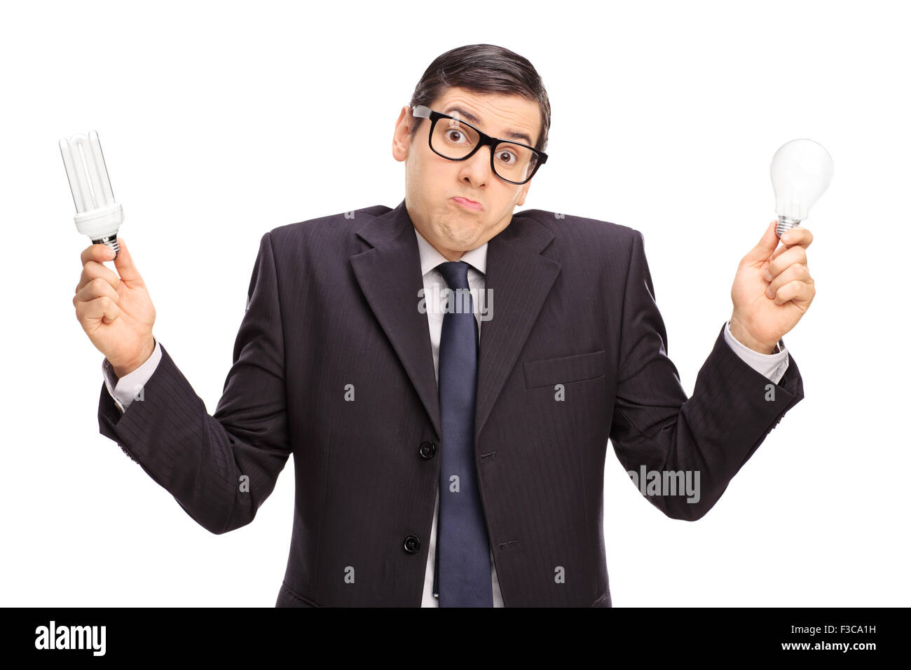 Confused businessman holding a normal light bulb in one hand and an