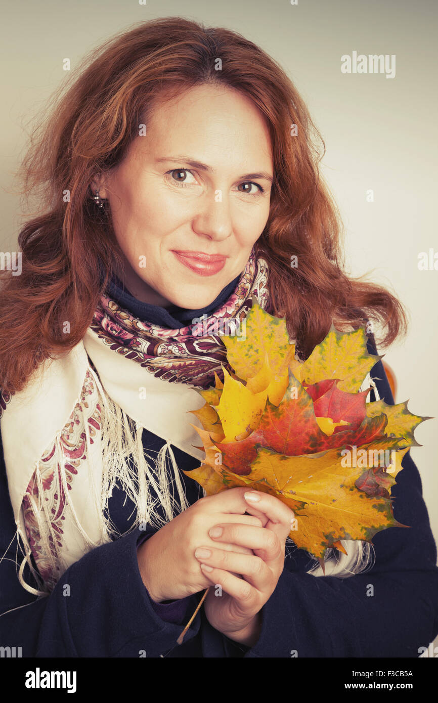 Portrait of beautiful Young Caucasian woman in traditional Russian neck scarf with colorful autumn maple leaves. Vintage tonal c Stock Photo