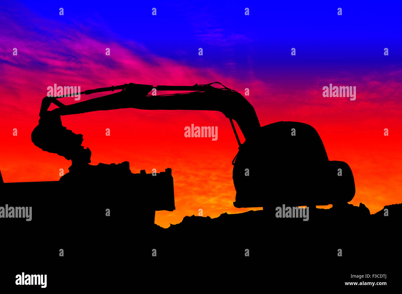 Silhouette Excavator loading dumper truck tipper in sandpit on sunset Stock Photo