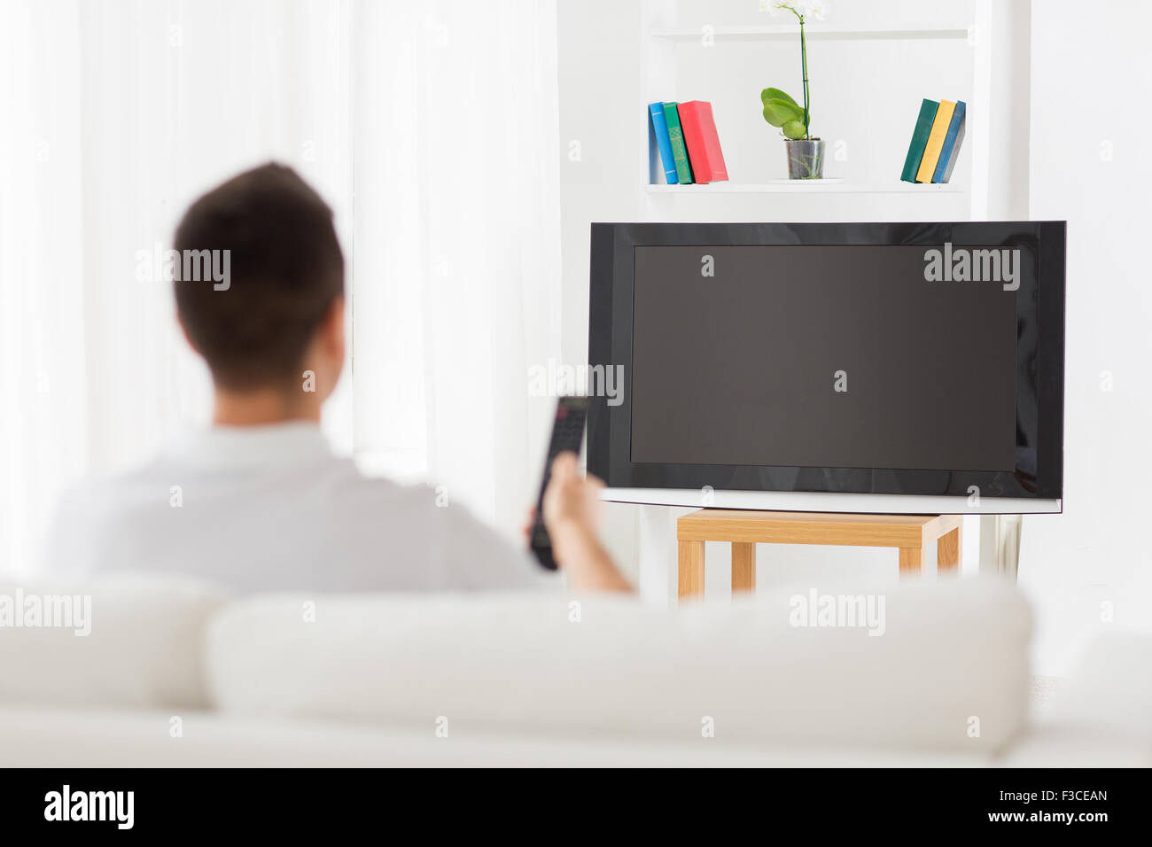 man watching tv and changing channels at home Stock Photo